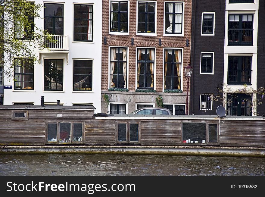 Dutch architecture. The barge is in the channel against the backdrop of the Amsterdam houses. Frontally. Fragment.