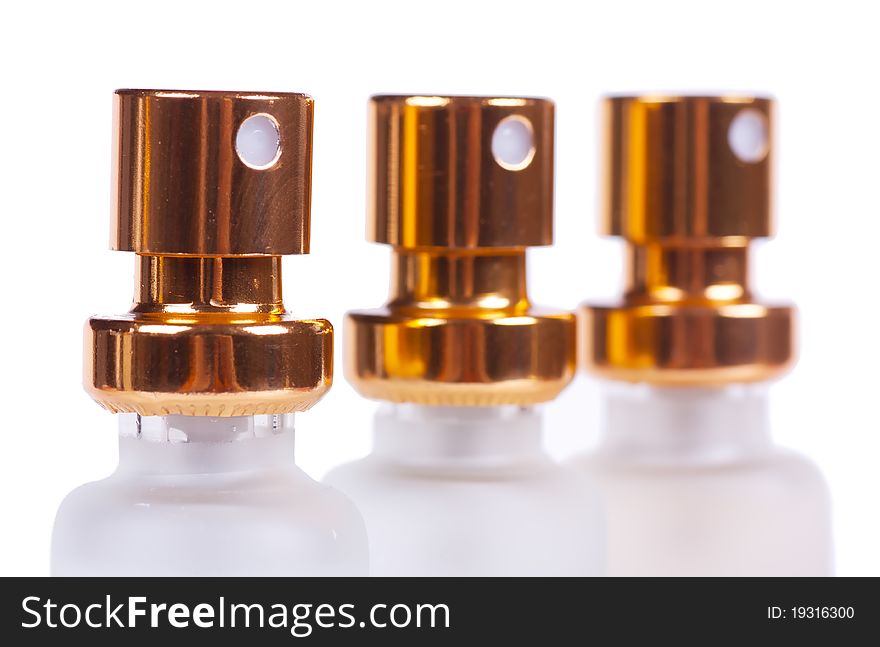 Sprayers of three perfume bottles isolated over white background. Macro view. Sprayers of three perfume bottles isolated over white background. Macro view.