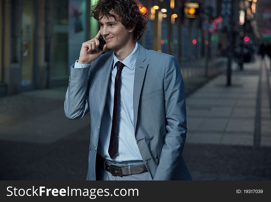 Handsome guy walking on a evening city street and calling