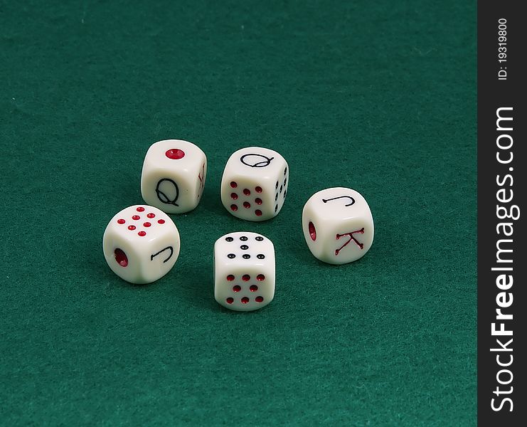 Five dice for the game of poker. On a green field.