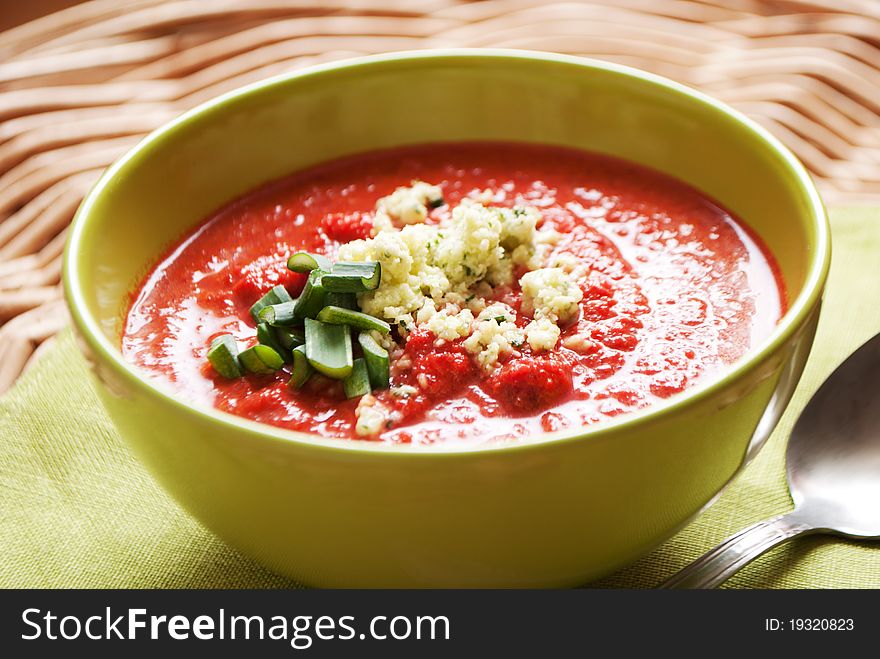 Bowl of tomatoes soup with cottage cheese and greens on top