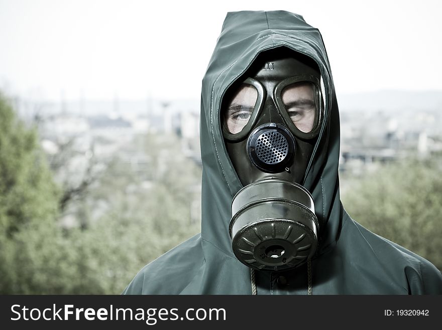 Man in gas mask on demolished industrial background with pipes
