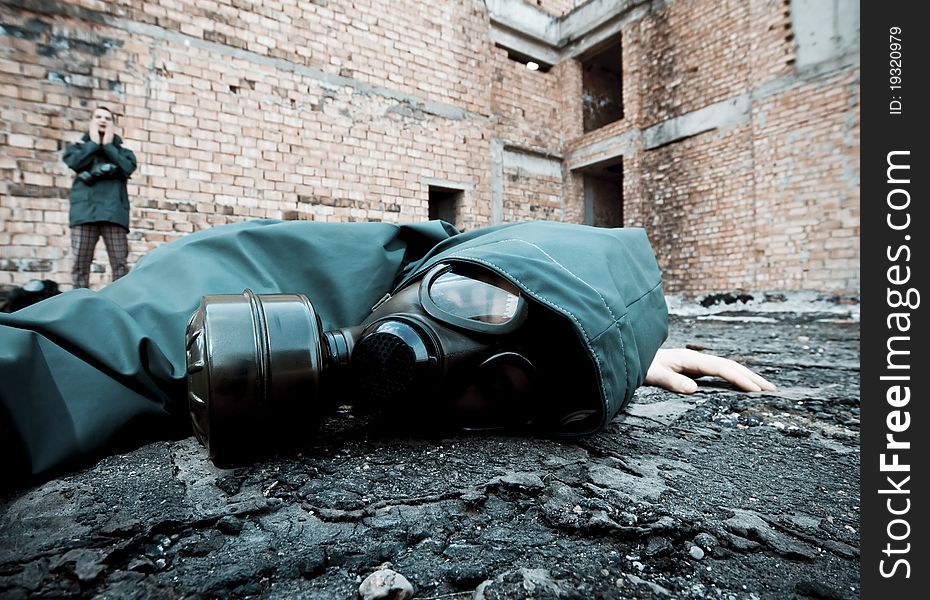 Man in gas mask fallen to the ground on demolished industrial background