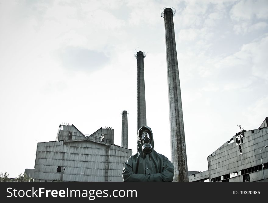 Man in gas mask on demolished industrial background with pipes