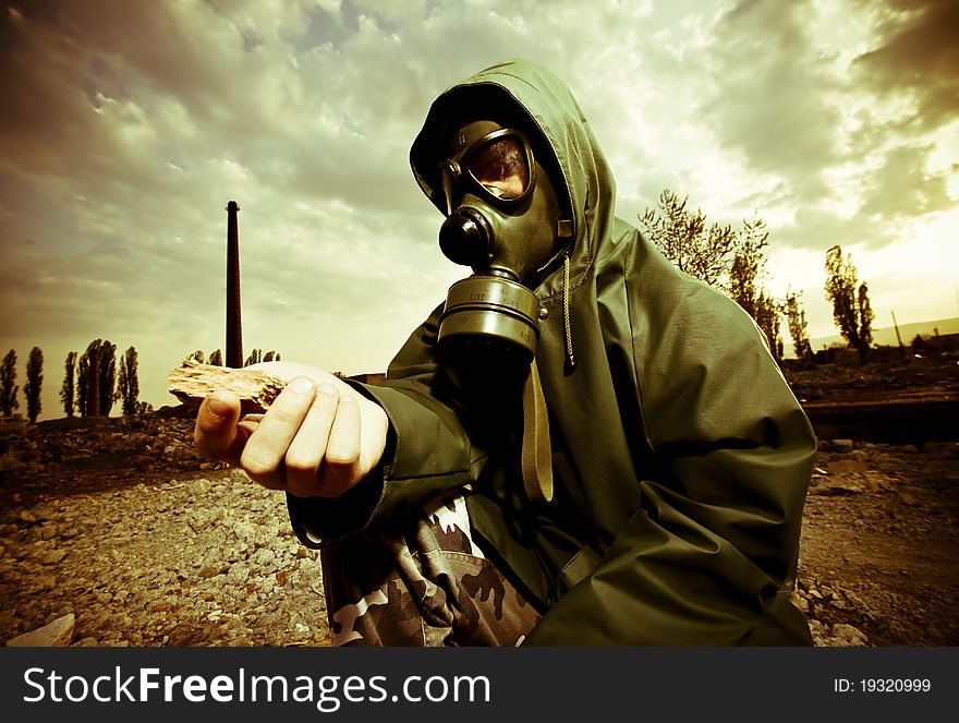 Scientist with gas mask examining rock in destroyed territory after explosion. Scientist with gas mask examining rock in destroyed territory after explosion