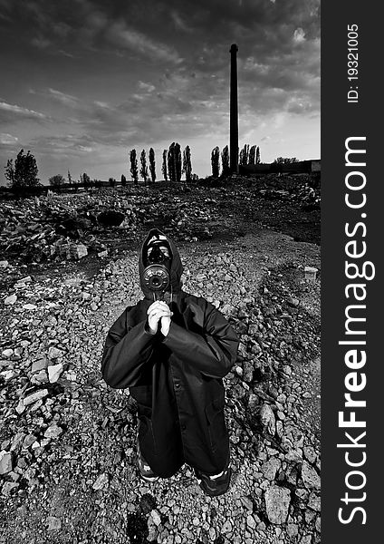 Scientist with gas mask praying in destroyed territory after explosion. Scientist with gas mask praying in destroyed territory after explosion