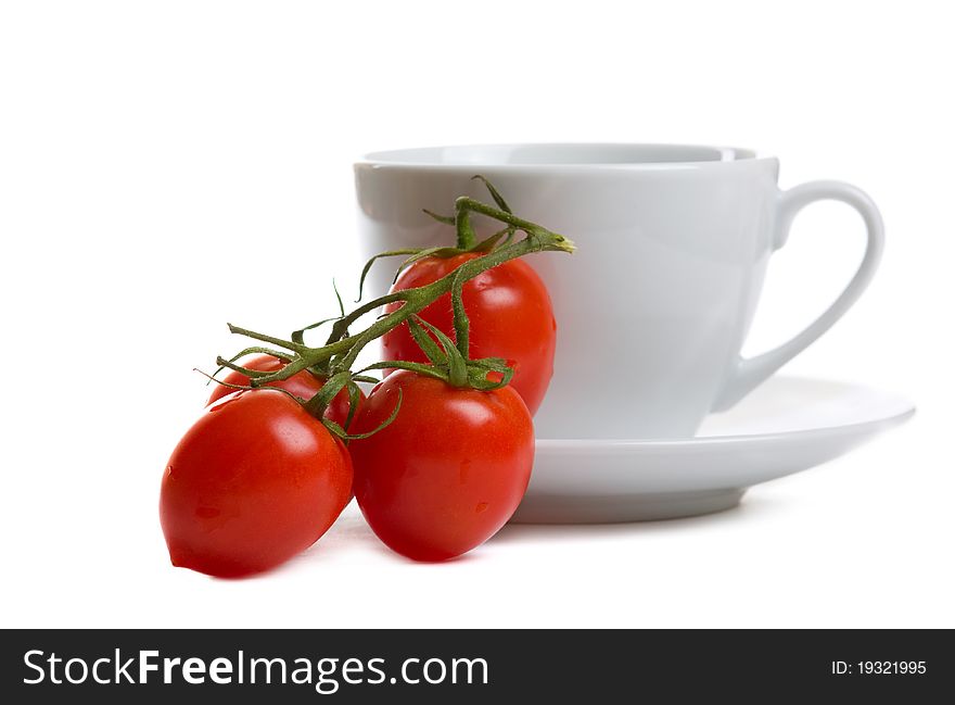 Branch of tomatoes and white cup isolated over white