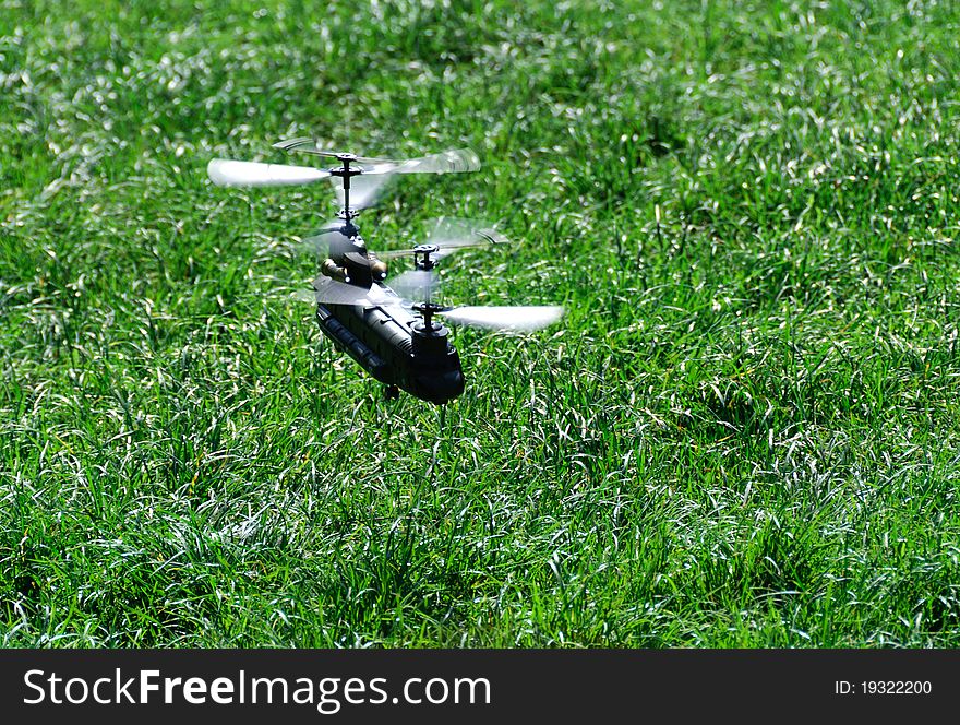 Model of a helicopter flying over a meadow