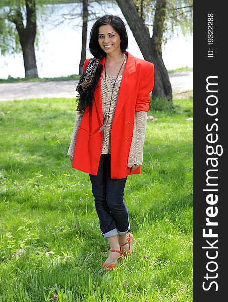 Beautiful brunette girl in red coat at the park