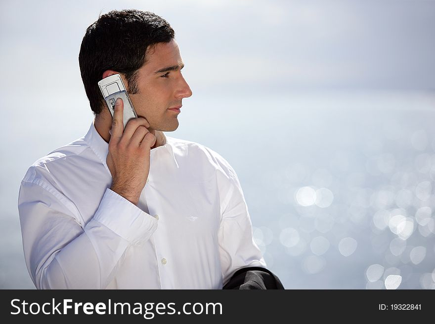 Young man in suit with a phone near the sea. Young man in suit with a phone near the sea