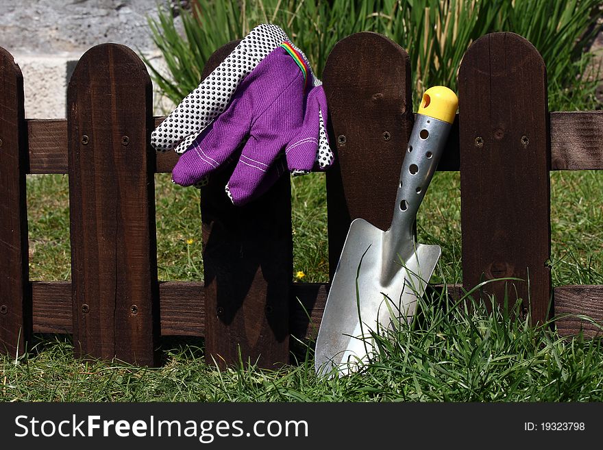 A shovel and gloves on a wooden fence in the garden