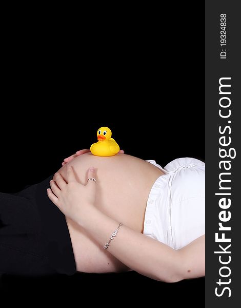 Colourful yellow toy duckie resting on top of a bare pregnant belly. isolated. Colourful yellow toy duckie resting on top of a bare pregnant belly. isolated
