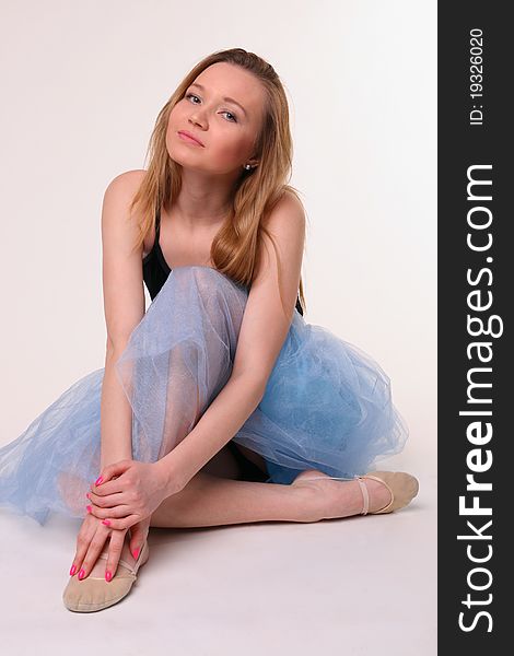 Beautiful young woman in dancing suit sits on floor and fold legs. Beautiful young woman in dancing suit sits on floor and fold legs.