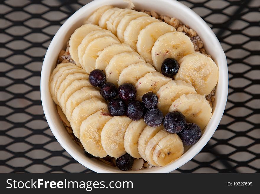 A healthy meal consisting of bananas, blueberries and granola