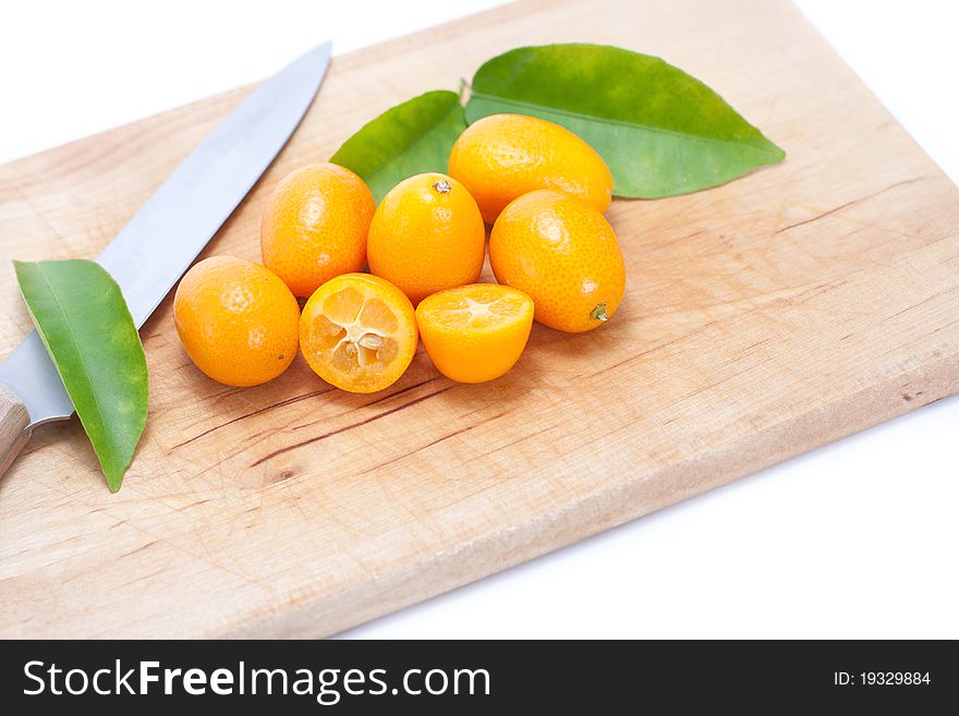 Kumquat on breadboard with knife and green leaves