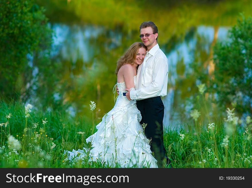 The bride and groom standing in the tall grass, illuminated by the evening sun. The bride and groom standing in the tall grass, illuminated by the evening sun