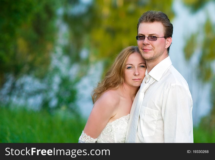 Young couple standing near a lake and looks at us. Young couple standing near a lake and looks at us