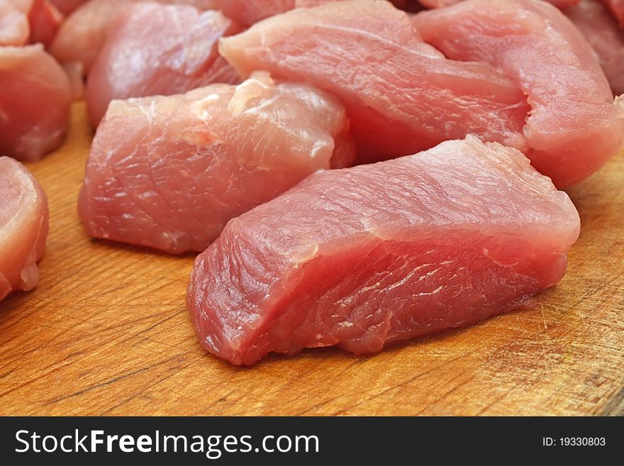 Raw meat chopped into large pieces on a wooden board. Raw meat chopped into large pieces on a wooden board
