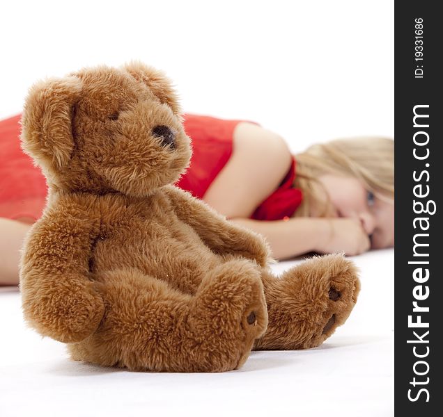 Little girl lying on floor in a red dress with her teddy bear infront of her. Little girl lying on floor in a red dress with her teddy bear infront of her.