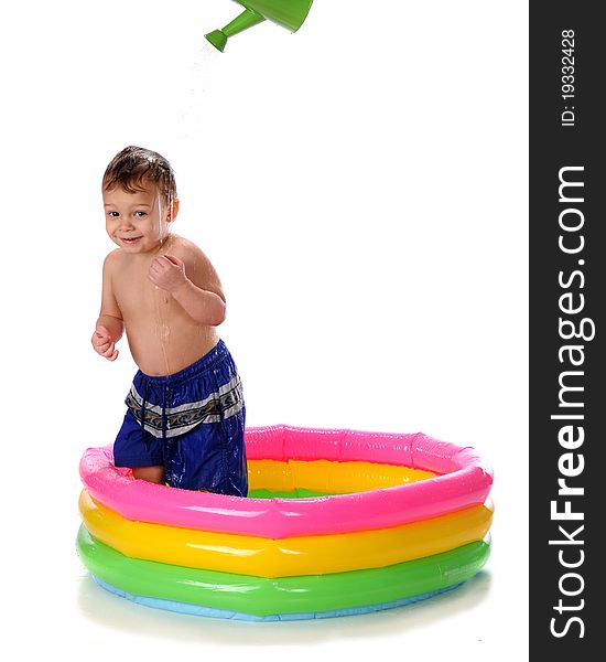 A happy toddler in a kiddie pool getting doused by a watering can. Isolated on white. A happy toddler in a kiddie pool getting doused by a watering can. Isolated on white.