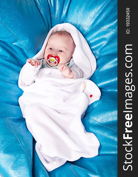 A baby wrapped up in the white swaddling band with the red dummy