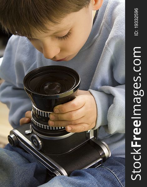 Young boy examining a vintage medium format camera. Young boy examining a vintage medium format camera