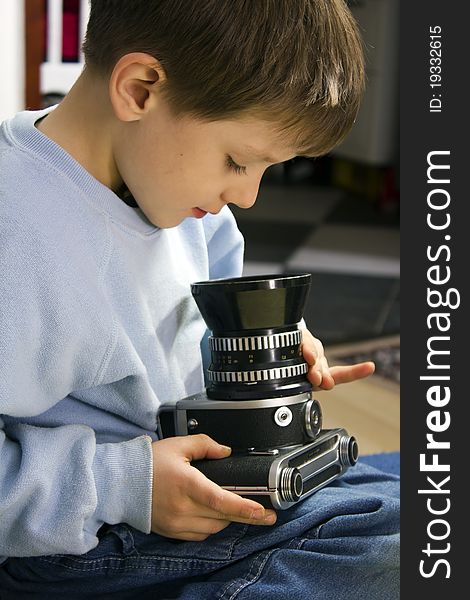 Young boy examining a vintage medium format camera. Young boy examining a vintage medium format camera