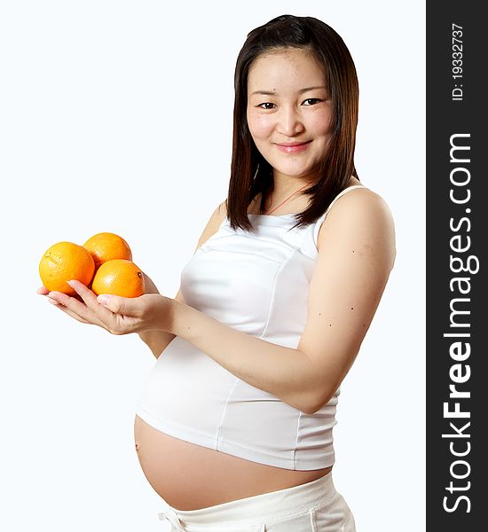 A young pregnant Asian woman with oranges for a healthy snack