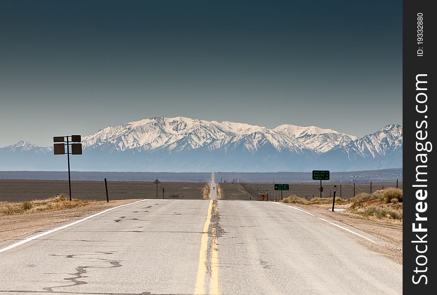 A very beautiful photograph of a road that leads down the valley to the mountains.