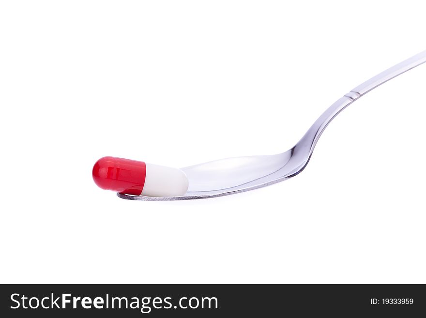 Single colored capsule on a spoon with white background