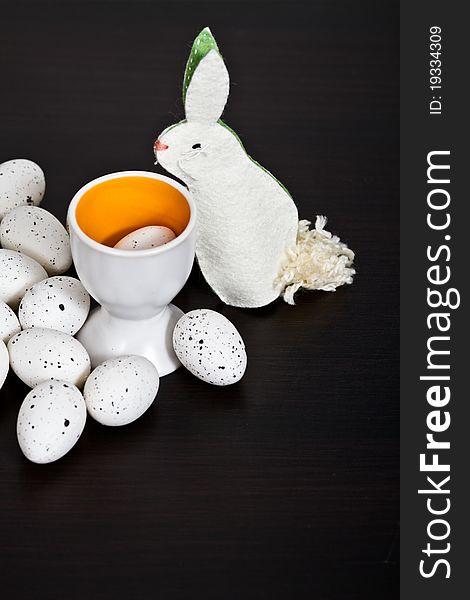 Quail eggs and handmade bunny on black background. Quail eggs and handmade bunny on black background
