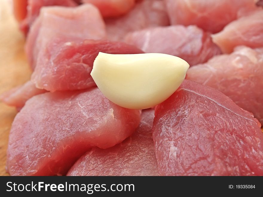 Raw meat cut into pieces with a clove of garlic. Raw meat cut into pieces with a clove of garlic