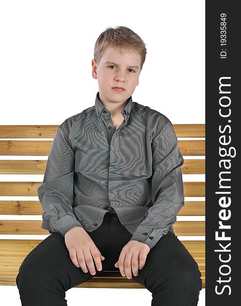 Serious boy sitting on a bench. Isolated