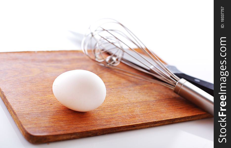 Eggs and whisk on white background