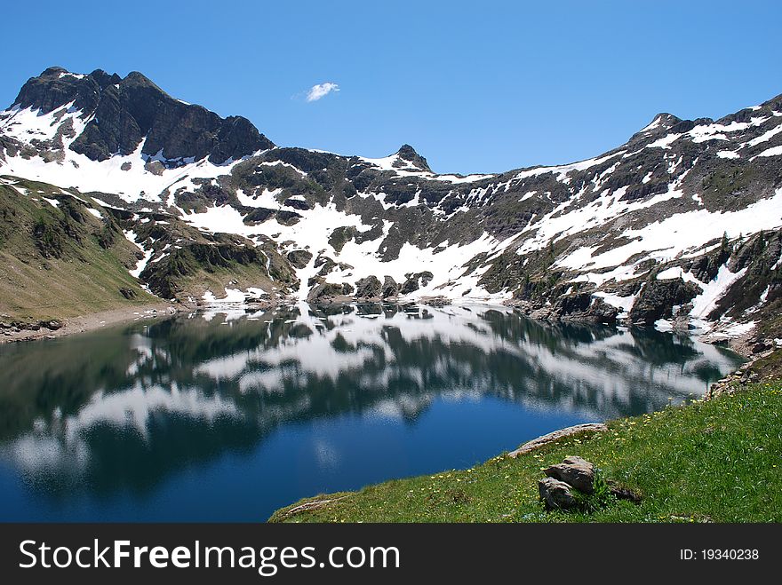 Mountain with snow is reflected in a mountain lake in the spring