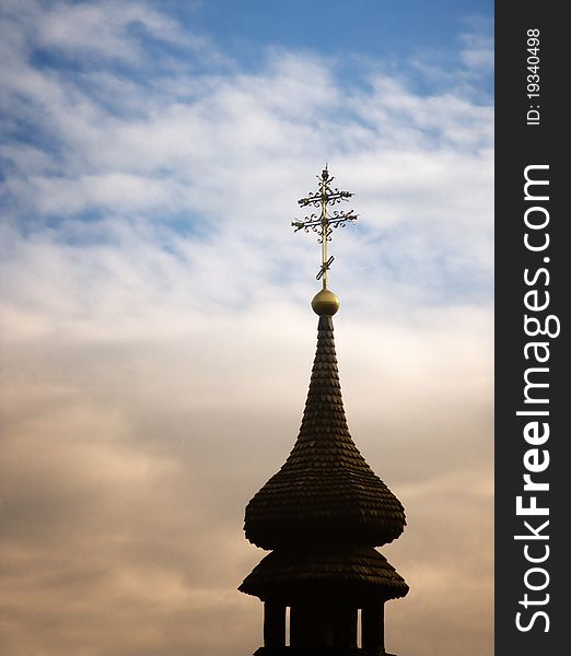 Gold cross and old wooden church silhouette at sunset sky. Orthodox cross made out of gold on roof of church tower made out of wood. Gold cross and old wooden church silhouette at sunset sky. Orthodox cross made out of gold on roof of church tower made out of wood.