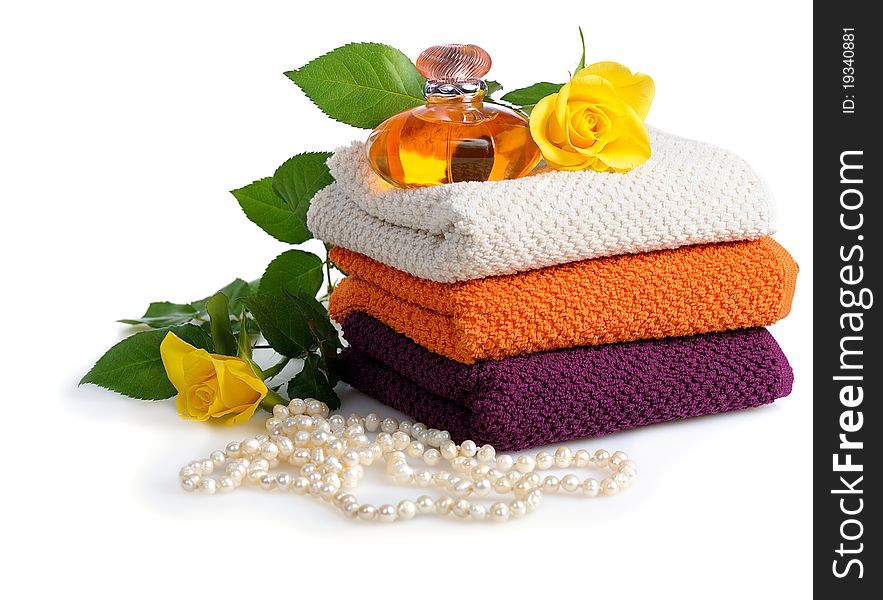 Yellow perfume bottle,roses and beads with towels on white background. Yellow perfume bottle,roses and beads with towels on white background