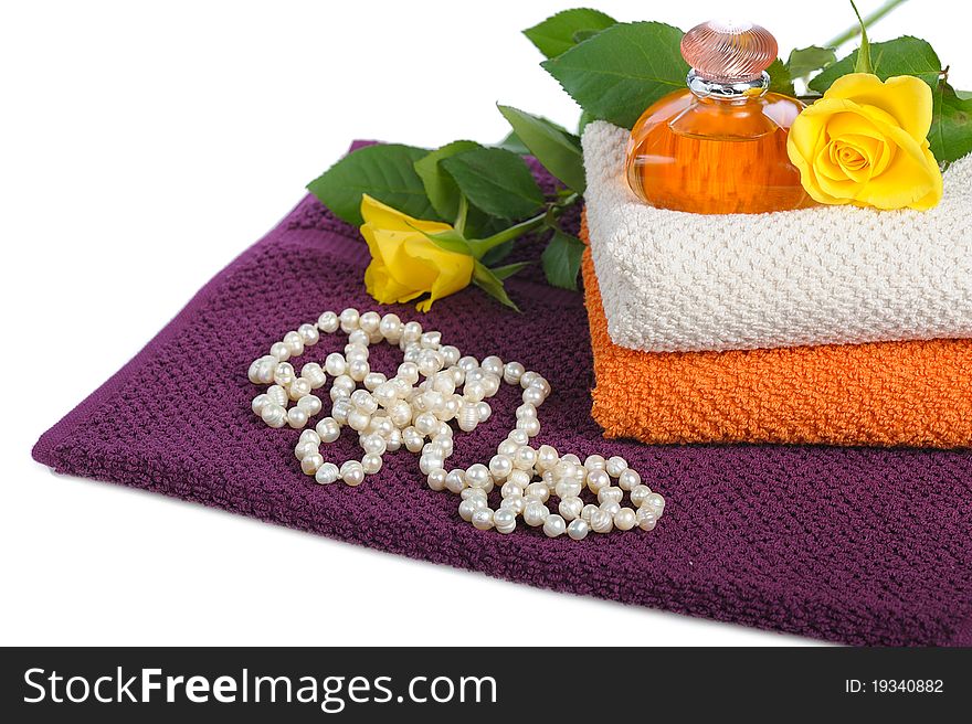 Yellow perfume bottle,roses and beads with towels on white background. Yellow perfume bottle,roses and beads with towels on white background