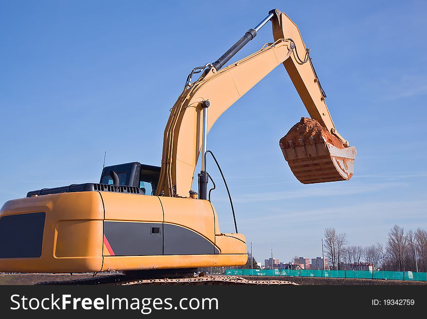 Excavator at construction site on a background of blue sky. Excavator at construction site on a background of blue sky