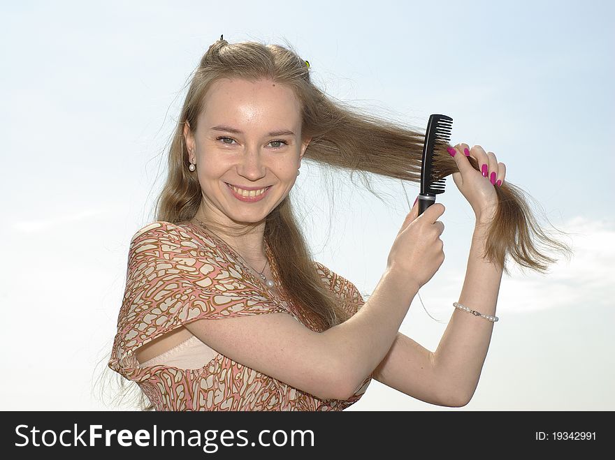 Smiling girl combing her light brown hair. Smiling girl combing her light brown hair