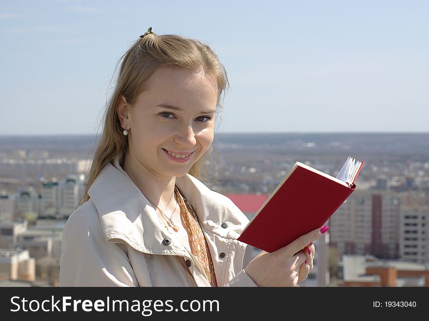 Girl with a red book with a cityscape in the background. Girl with a red book with a cityscape in the background