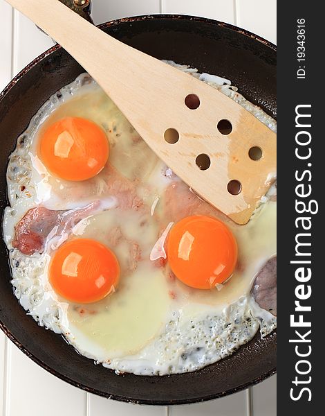 Preparing ham and eggs in a frying pan