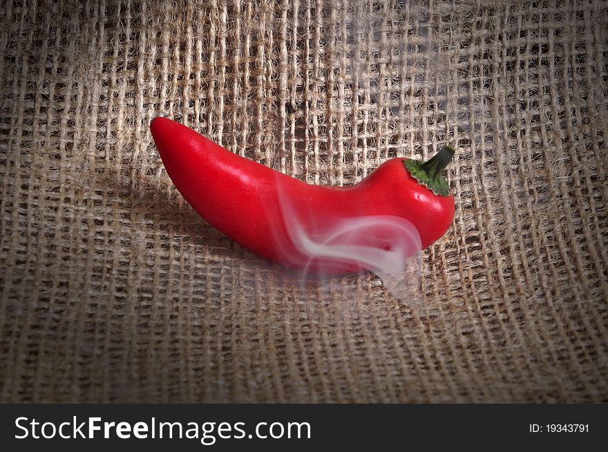 A smoking hot chilli, photographed in a studio.