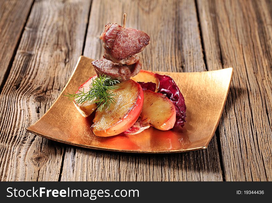 Roasted meat on stick and slices of apple. Roasted meat on stick and slices of apple