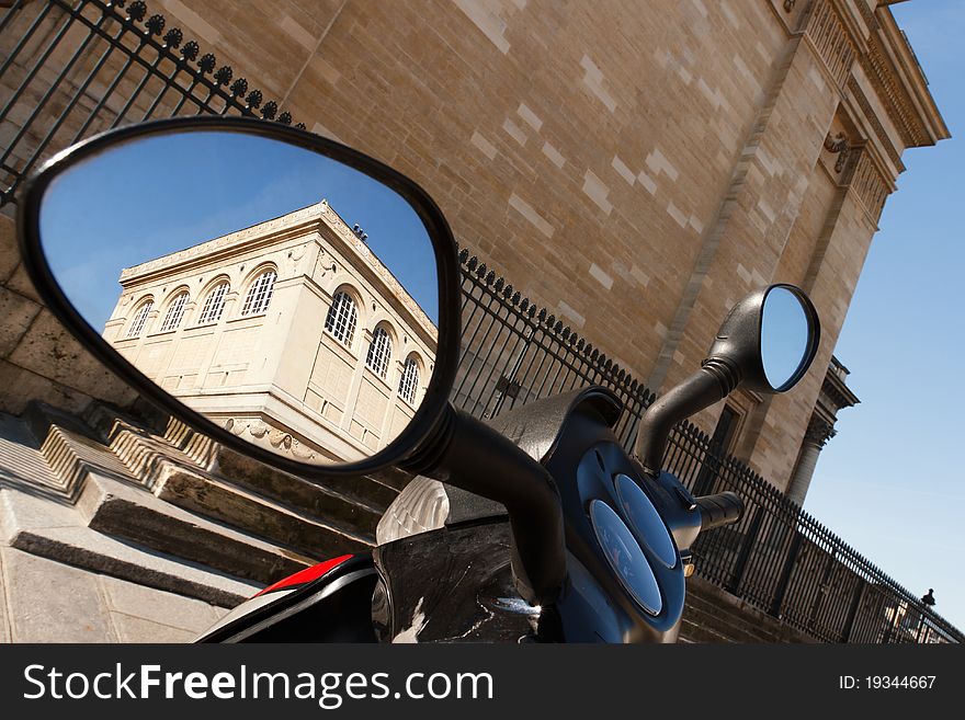 A historic building in Paris seen in a motorbike's rearview mirror. A historic building in Paris seen in a motorbike's rearview mirror