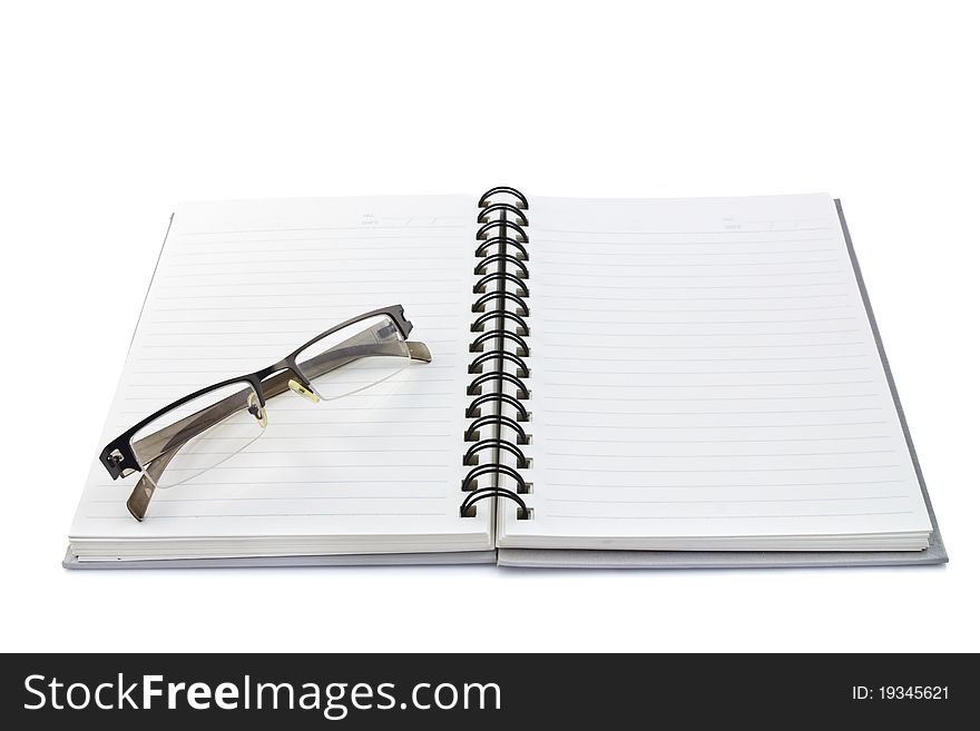 Plastic glasses on spiral notebook isolated on white background. Plastic glasses on spiral notebook isolated on white background