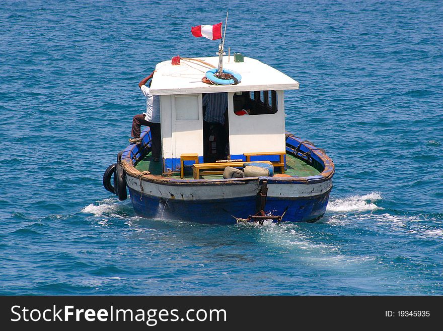 Old boat with cabin is sailing away, visible aft and Peruvian flag. Old boat with cabin is sailing away, visible aft and Peruvian flag