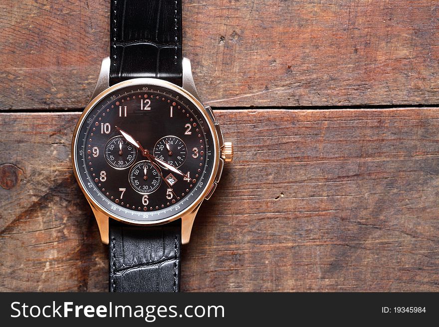 Closeup of modern wristwatch lying on wooden surface. Closeup of modern wristwatch lying on wooden surface