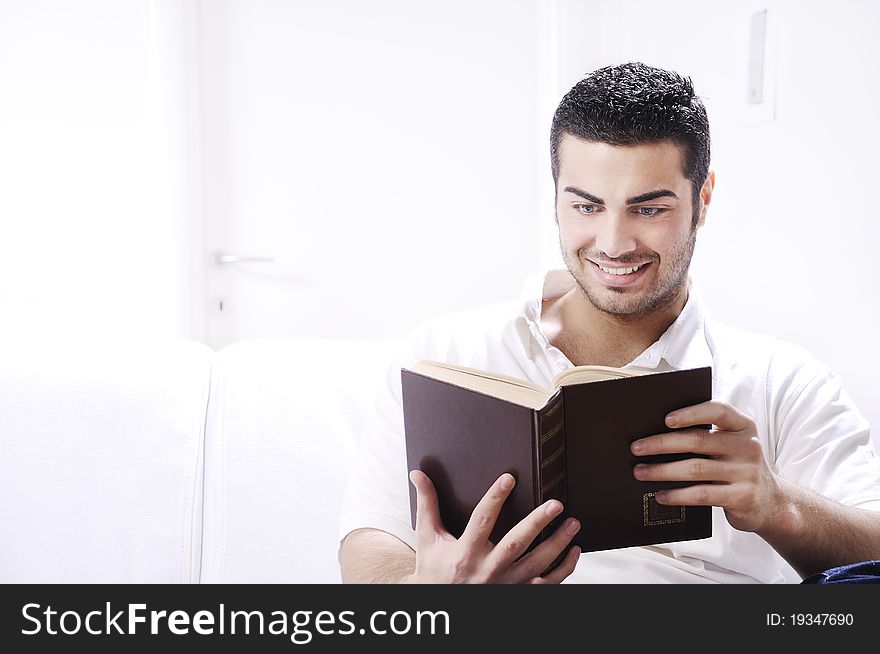 Young man reading book in home interior on white background