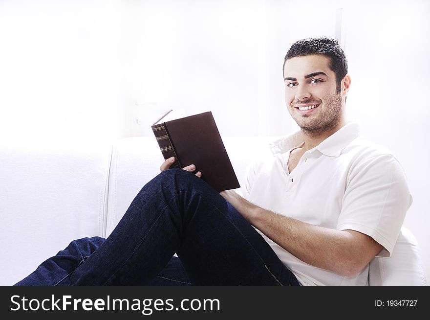 Young man reading book in home interior on white background